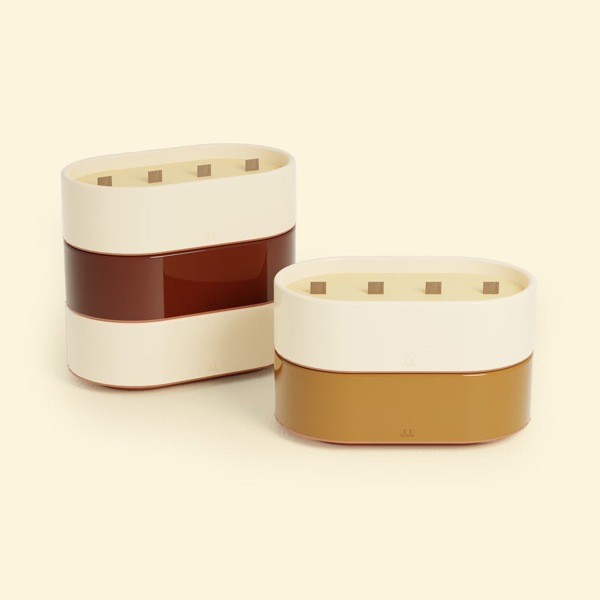 Bougies Totem L Beige ivoire – Citronnelle & Citron, Rouge oxyde – Citronnelle & Géranium et Brun terre de sienne – Citronnelle & Fleur d’oranger, deux grandes bougies ovales à triple mèche en bois, posées sur un fond beige clair.