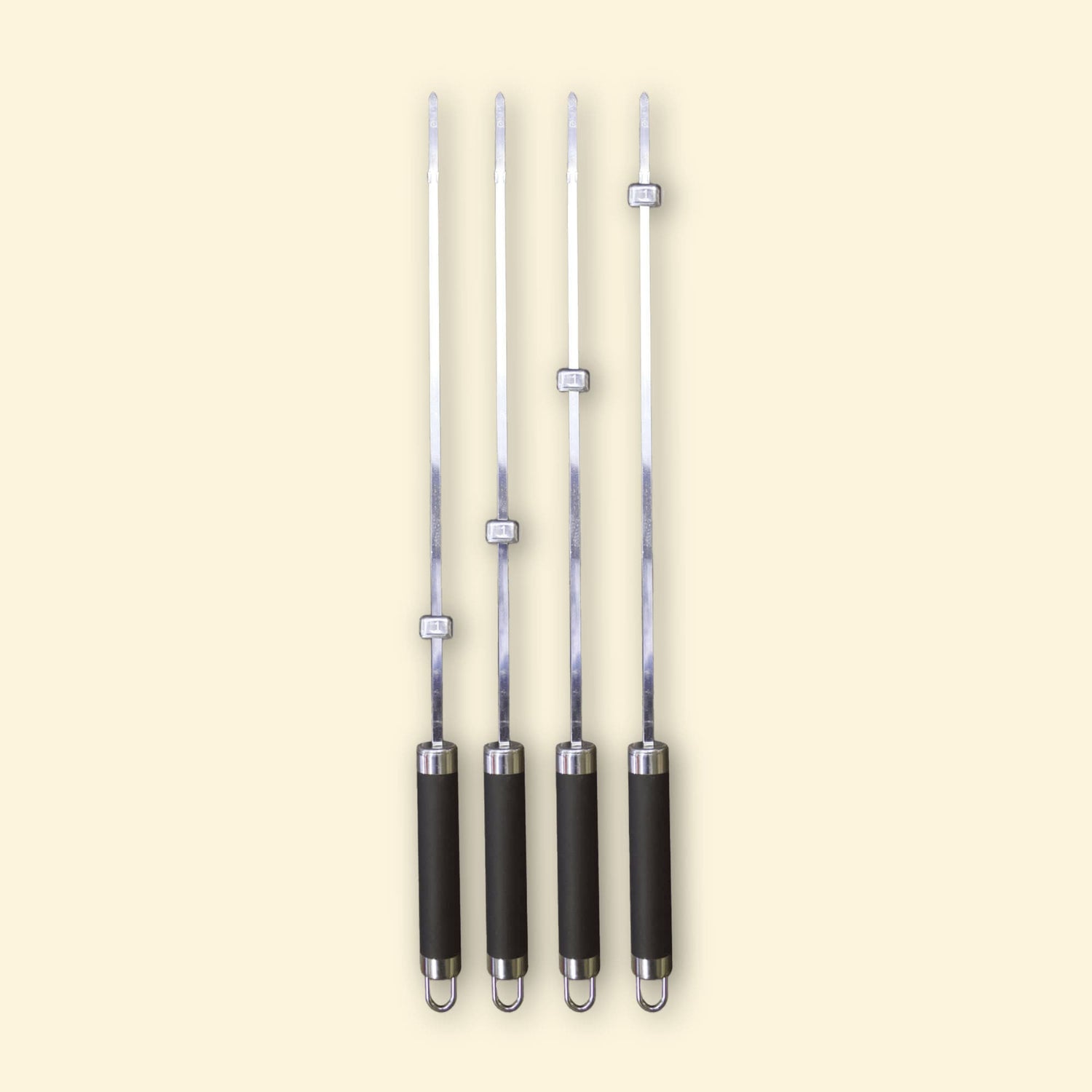 Lot de quatre brochettes longues en inox avec manche noir et bagues réglables, alignées sur fond beige.