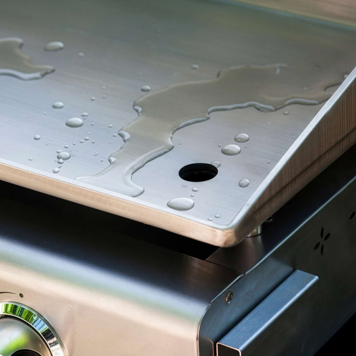 Rinçage de la plaque de cuisson d’une plancha Vivaplancha à l’eau pour un nettoyage rapide après utilisation